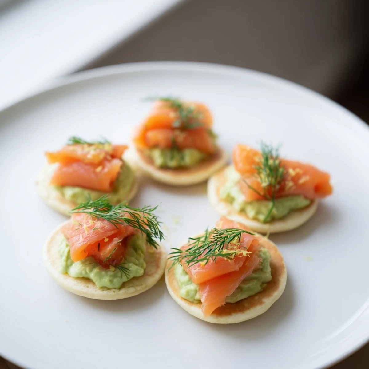 Fluffy quark blinis topped with smoked salmon, creamy avocado, ready for brunch.