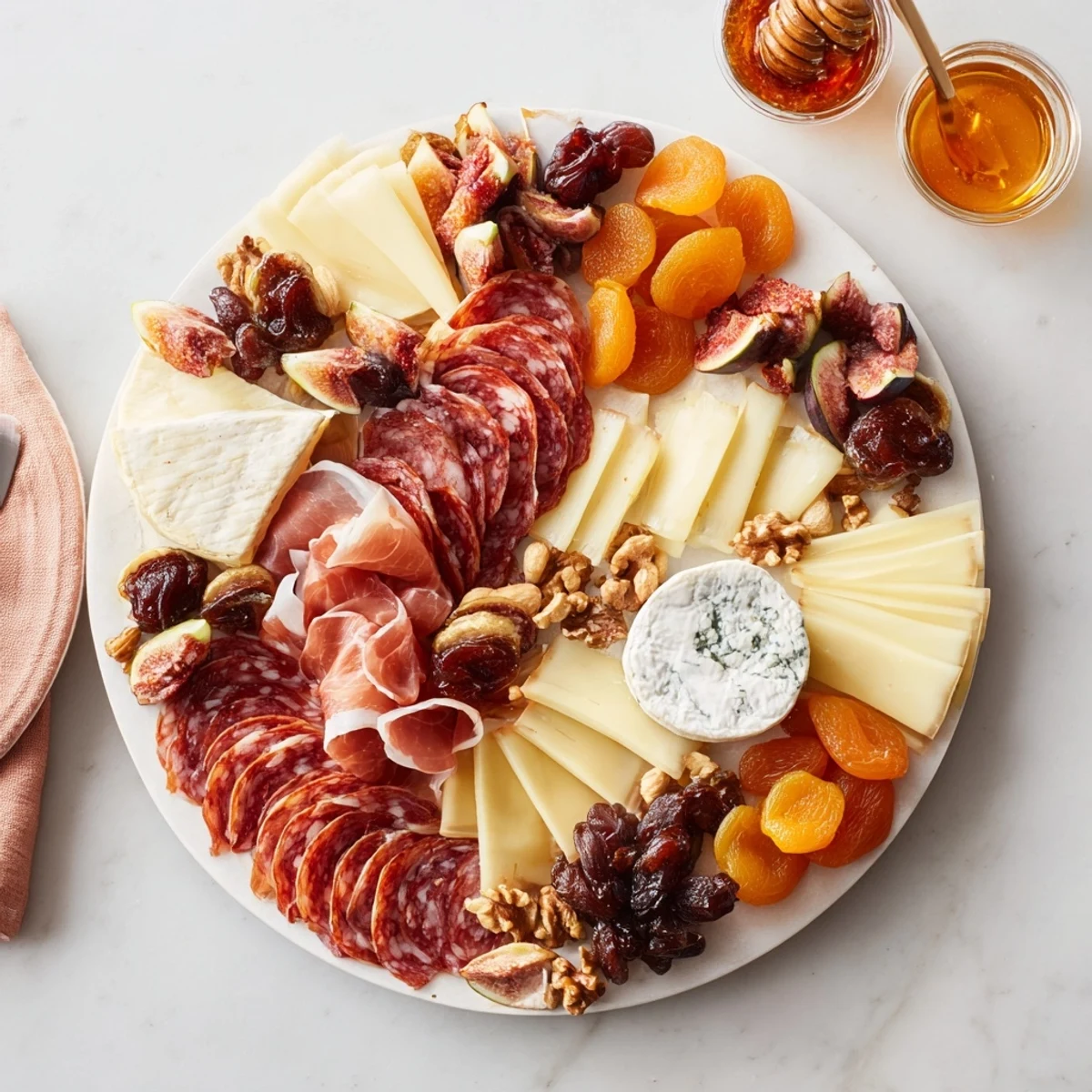 Elegant arrangement of Plateau des Rois Mages Gourmand, highlighting cheeses, meats, dates, and nuts with honey for serving.