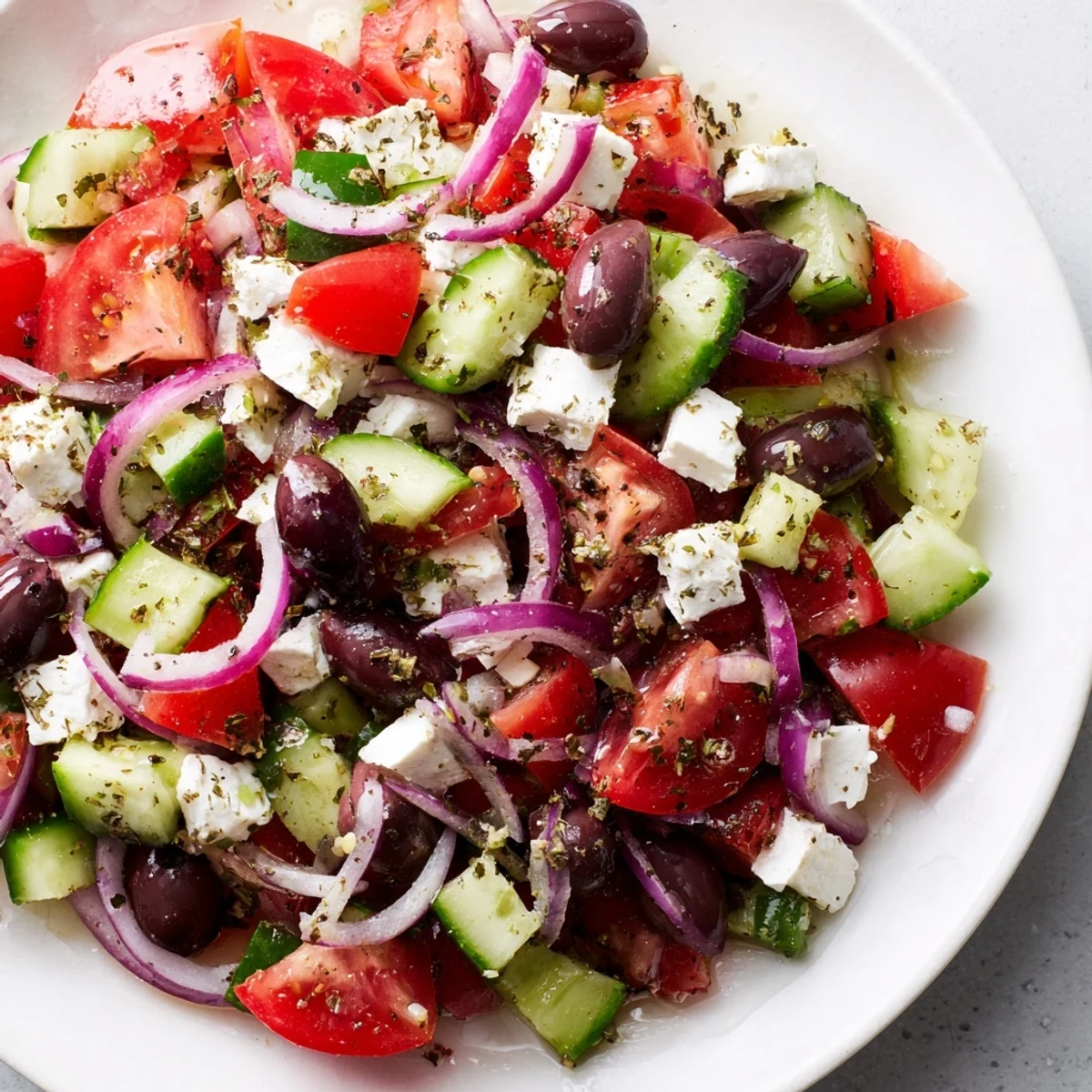 A fresh Mediterranean salad, showcasing vibrant tomatoes, olives, and creamy feta cheese, ready to eat.