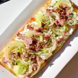 Golden, bubbly sheet-pan Flammkuchen, Alsatian style, topped with crème fraîche, bacon, and leeks.
