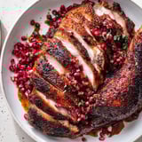 A close-up of sliced roasted duck breast with vibrant pomegranate reduction, ready to serve.