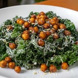 A close-up of the Warm Kale Salad with Crispy Chickpeas, showing textures and the vibrant dressing.