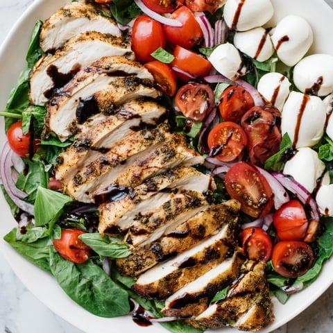 Grilled Caprese Chicken Salad with juicy chicken, fresh tomatoes, and creamy mozzarella, drizzled with balsamic glaze.