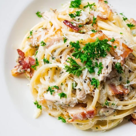 Die leckeren Hühnchen Carbonara schmecken auf einem breiten Teller mit frisch geriebenem Parmesan bestreut.