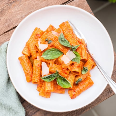Gekochtes Spicy Rigatoni Pasta in einer cremigen, scharfen Tomatensauce, garniert mit frischem Basilikum und geriebenem Parmesan für US-Foodie-Fotos.  