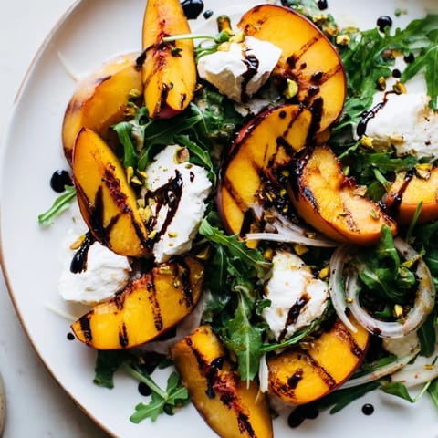 A fresh, colorful Grilled Peach Salad with grilled peach slices, arugula, and creamy burrata cheese.