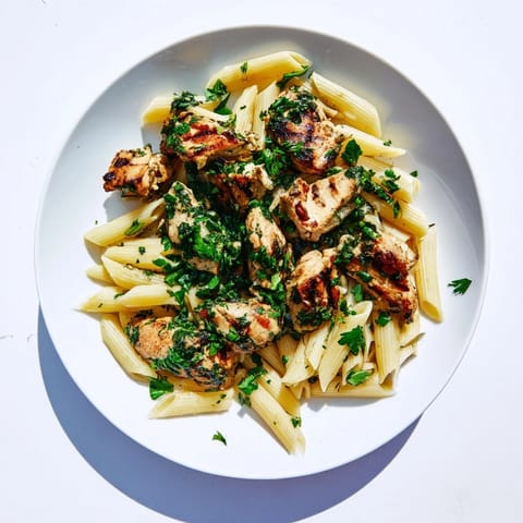 Chimichurri Chicken Pasta mit saftigem gegrilltem Hühnchen auf Al-dente-Penne in lebendiger, herber Kräutersauce serviert, frisch mit Zitronenscheiben garniert für südamerikanischen Fusion-Genuss.  