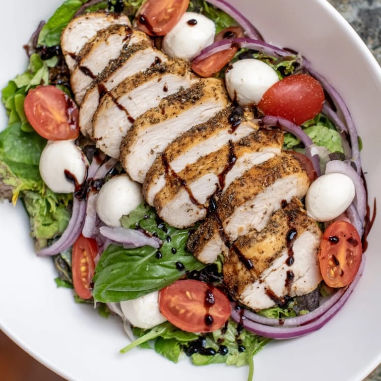 A close-up of vibrant Caprese Chicken Salad, showcasing grilled chicken and fresh basil, ready to eat.